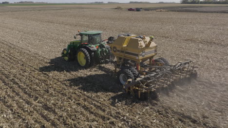 tractor pulling strip till machine, preparing soil on farm field for planting, aerial