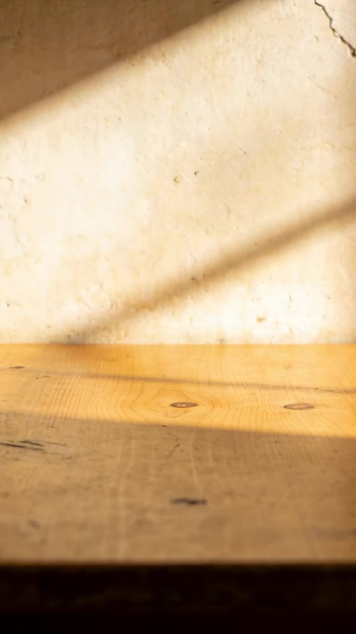 Video verticale: Luce solare che si sposta, attraversando un tavolo di legno e una parete di intonaco all'interno, rivelando una crepa.