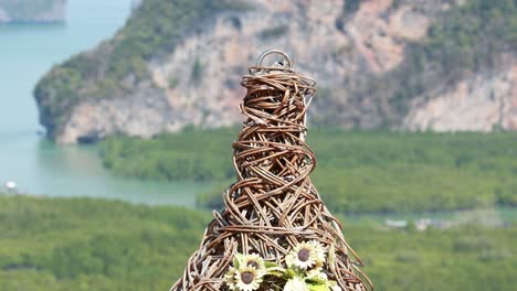 a wicker arch adorned with flowers frames a lush, green landscape in phuket, thailand, under bright natural lighting