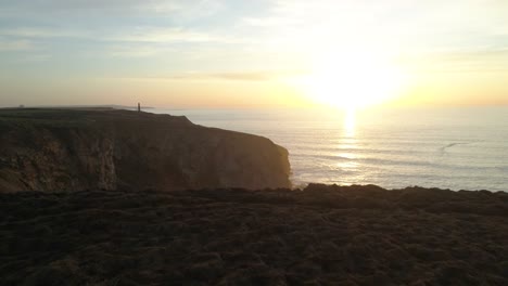 cinematic aerial of cute couple four by four vehicle along ocean cliffs at beautiful sunset