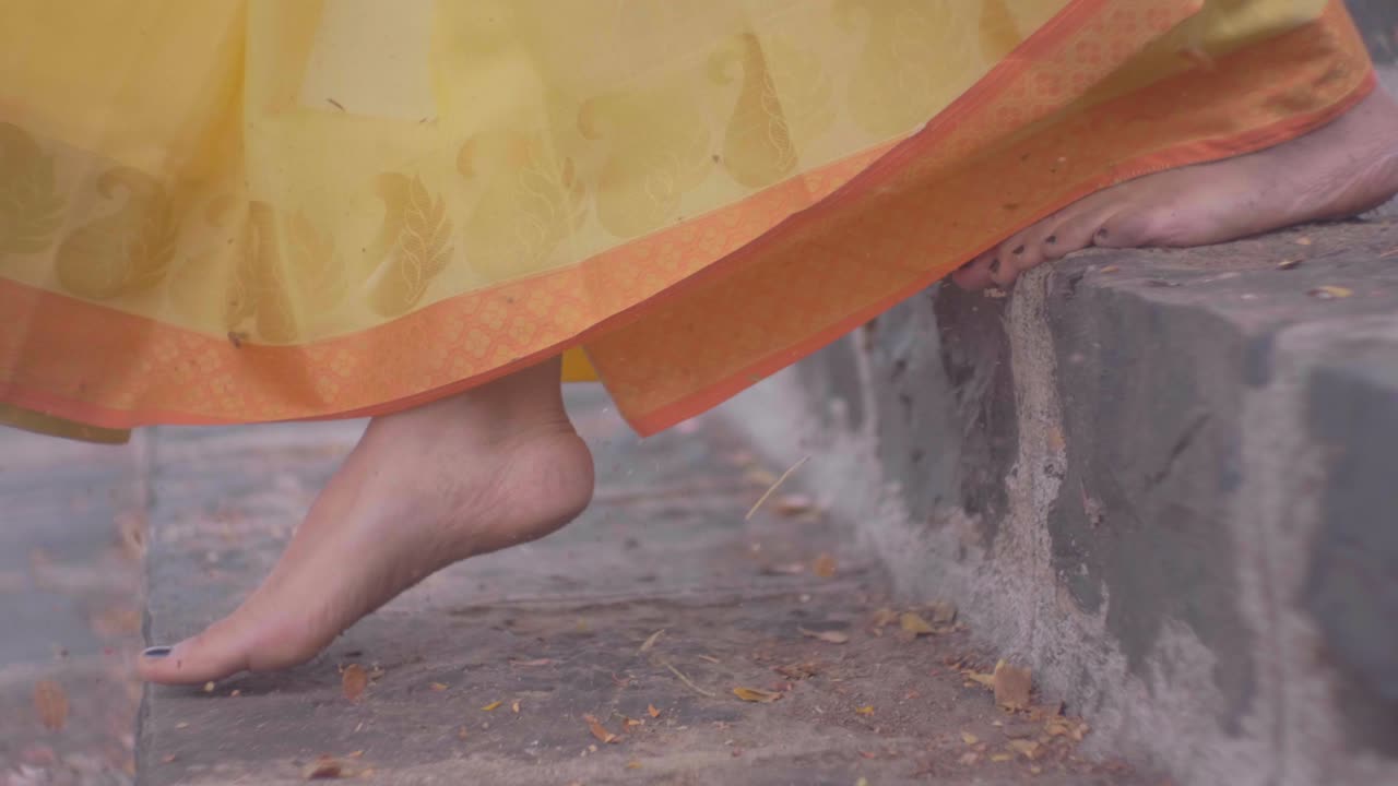 mädchen in gelbem saree kommt in zeitlupe von der treppe am seeufer herunter