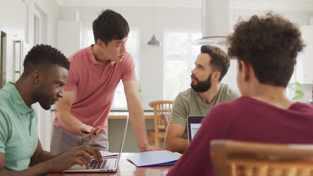 diversos amigos hombres felices hablando y usando computadora portátil en la sala de estar