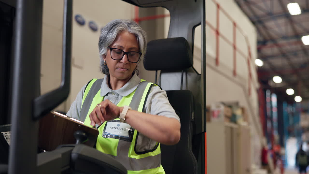 Woman in Safety Vest Writing on Clipboard in Warehouse