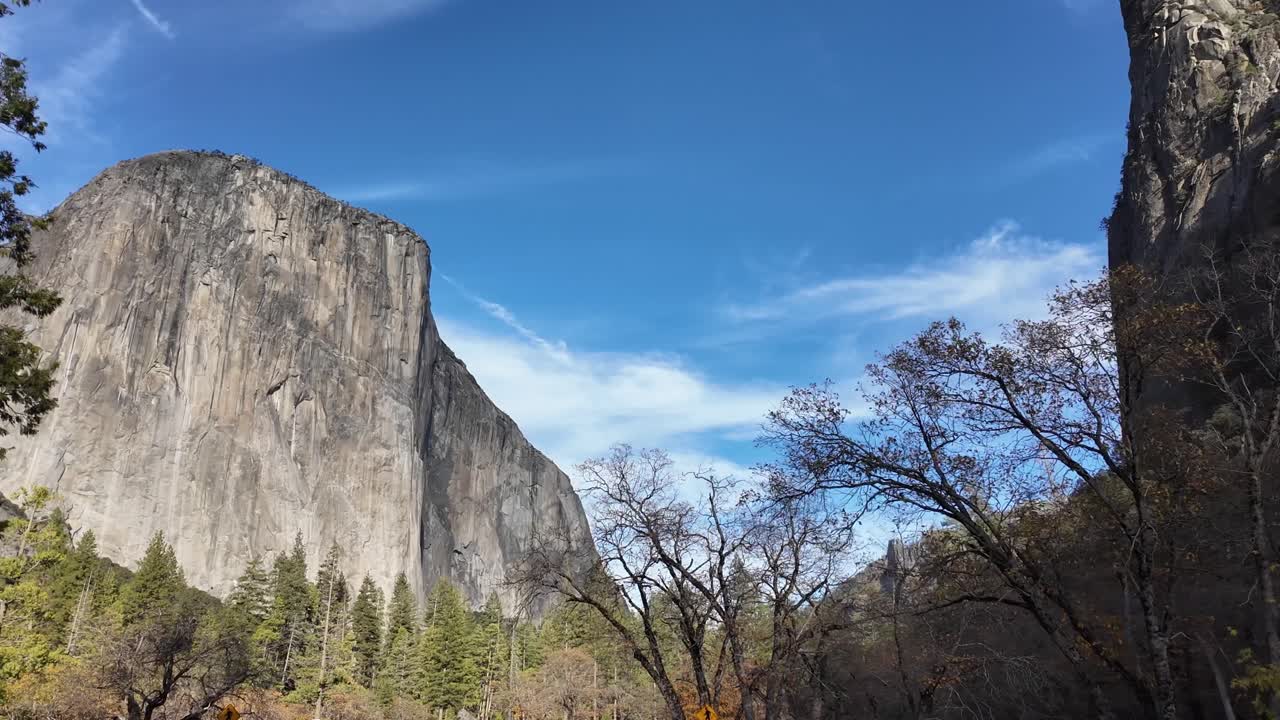 El Capitan rises sharply above Yosemite Valley as seen from the main road, its massive granite face catching soft daylight across the open valley floor