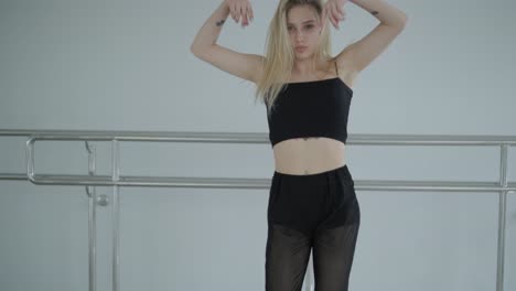 fit girl in black clothes performing contemporary. female dancer shows flowing motions, body and hands waves at white room. modern ballet dance choreography. young woman is moving smoothly