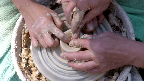 potter's hands work with clay on a potter's wheel