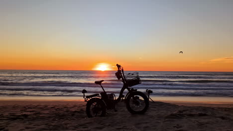 Silueta-De-Un-Triciclo-De-Bicicleta-Eléctrica-En-Una-Playa-Al-Atardecer