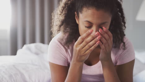 woman wearing pajamas suffering with depression sitting on bed at home