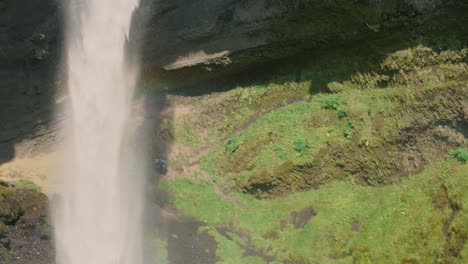 hombre tocando la guitarra frente a una hermosa cascada en islandia-16