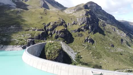 Vuelo-De-Drones-Sobre-La-Pared-De-La-Presa-Del-Hermoso-Lago-De-Moiry-En-Las-Montañas-Suizas,-Super-Paisaje