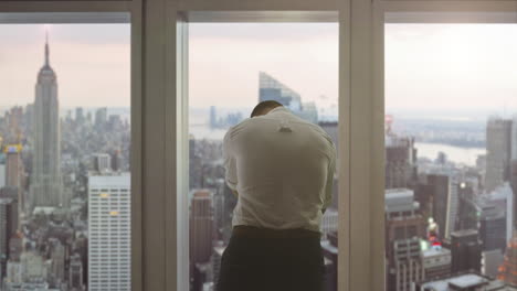 businessman looking out of skyscraper window in new york city