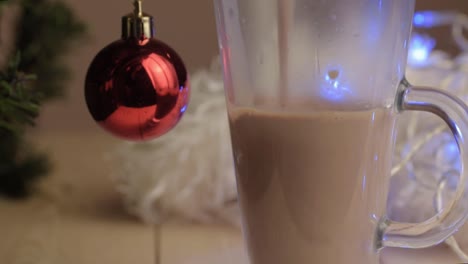 Pouring-hot-chocolate-drink-into-glass-mug-with-Christmas-background