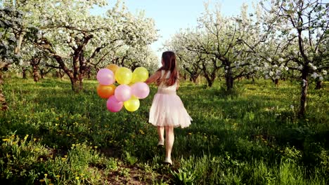 happy girl with balloons running in the blooming garden