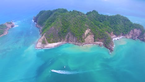 drone video overlooking a green island off costa rica surrounded by incredible turquoise blue water from the pacific ocean