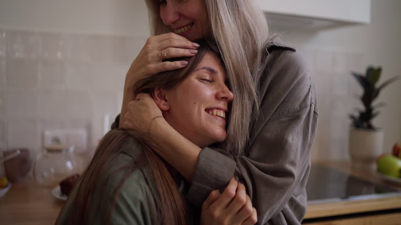 dos mujeres abrazadas en la cocina.