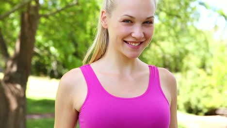 Fit-blonde-measuring-her-waist-in-the-park