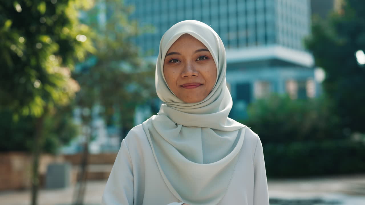 Smiling woman in hijab holding a Palestinian flag outdoors