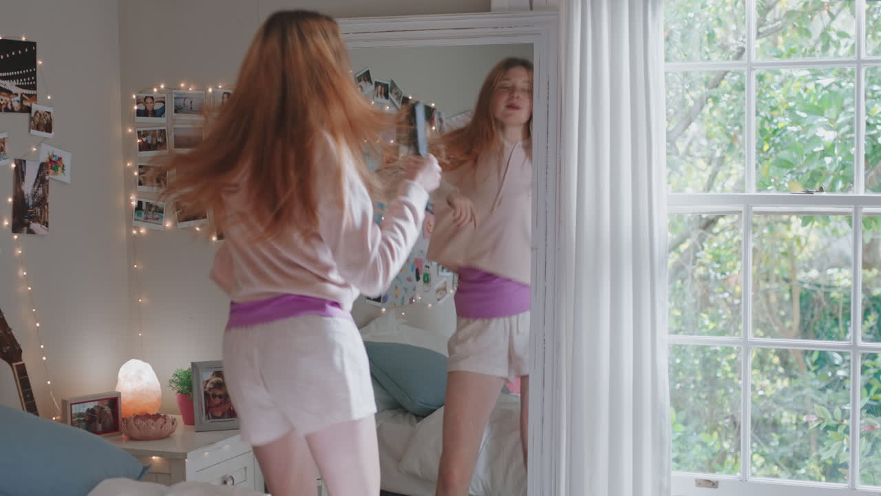 행복한 십대 소녀가 침실에서 음악에 맞춰 춤을 추고 주말을 축하하고 재미있게 노래하며 집에서 파자마를 입고