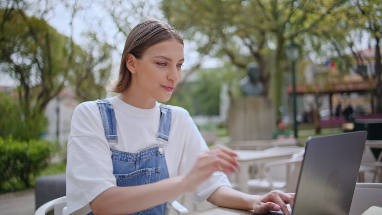 Positive girl working laptop at street cafe enjoy tasty cappuccino closeup