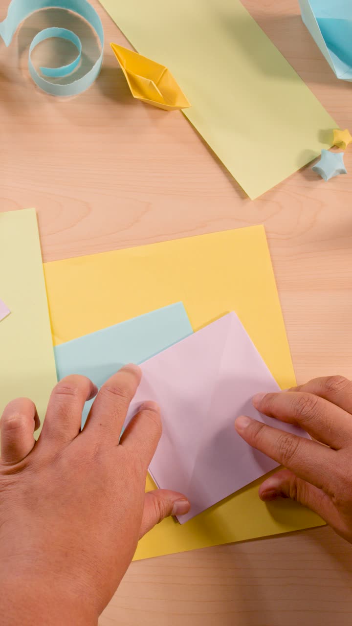 Mani che piegano carta origami su un tavolo di legno