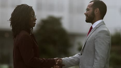 cheerful colleagues shaking hands in park