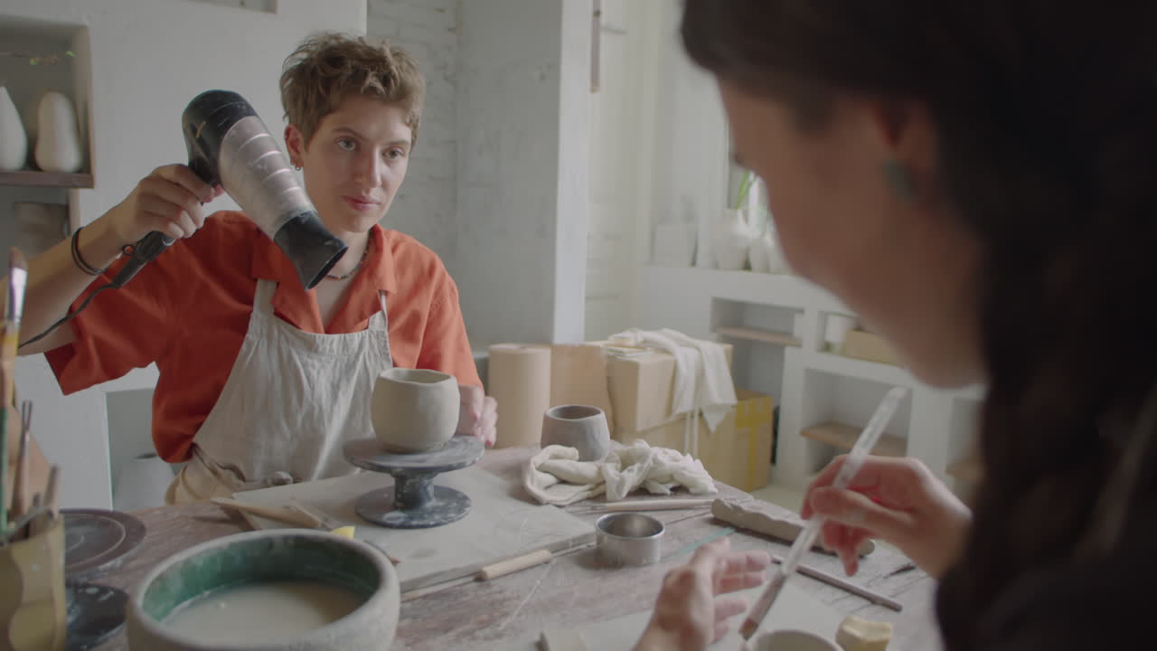 Woman Drying Ceramics with Hairdryer at Craft Workshop