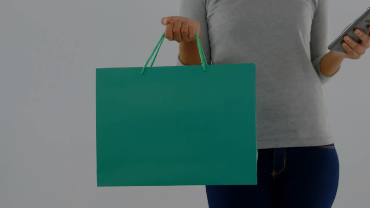 Woman holding teal bag, glancing at phone and smiling while finance charts overlaying for insights