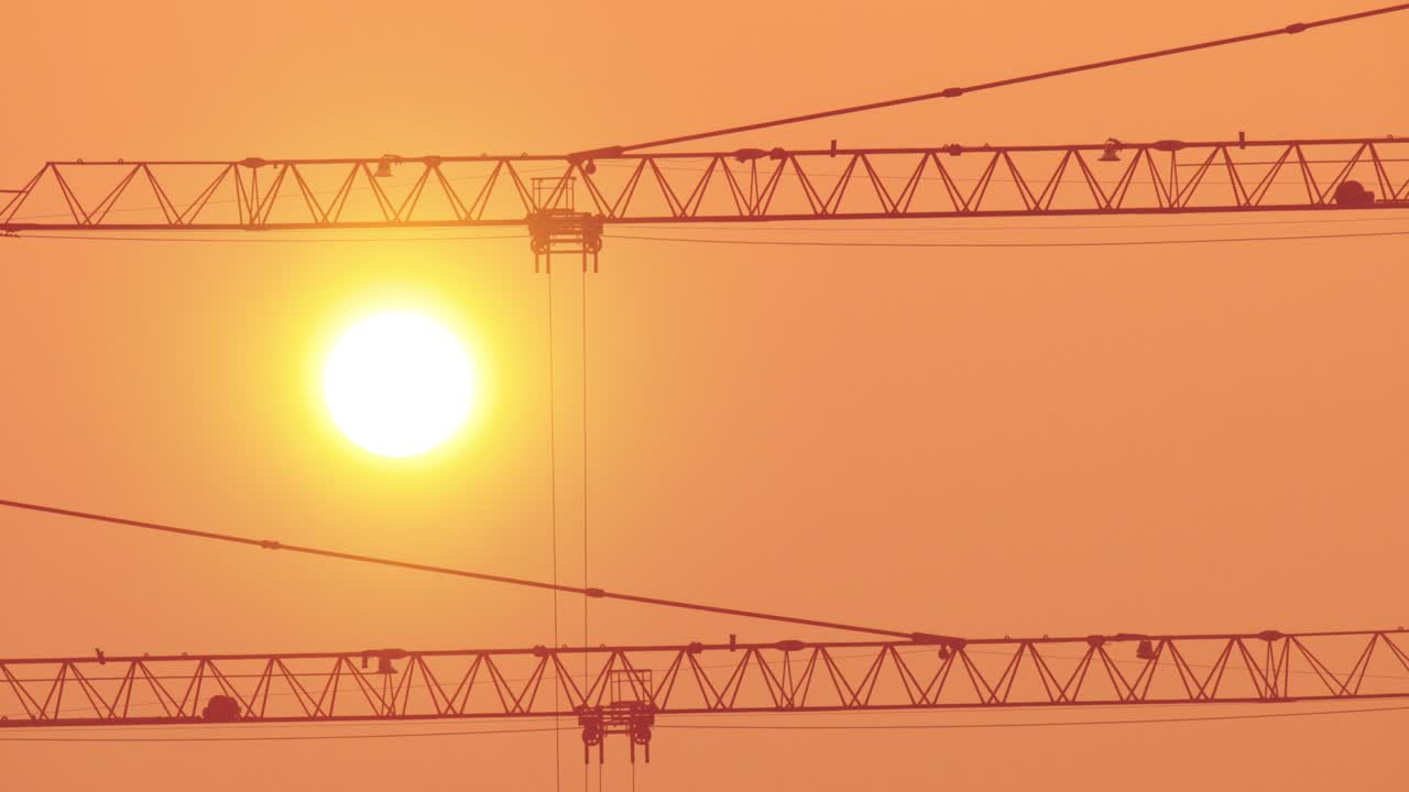 la grúa de construcción trabaja contra la brillante puesta de sol