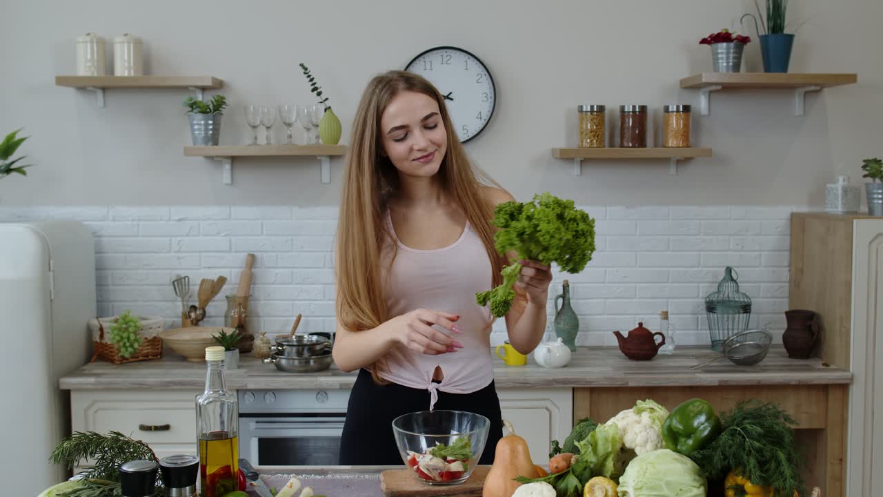 chica joven bailando, divirtiéndose y cocinando ensalada con verduras crudas. arrojando pedazos de lechuga