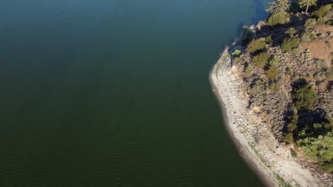 Lake-Hemet-coastline-and-beach,-aerial-tilting-up-view