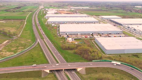 Aerial-Shot-of-Industrial-Warehouse-Storage-Building-Loading-Area-where-Many-Trucks-Are-Loading-Unloading-Merchandise