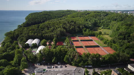 arka tennis club courts surrounded with green forest by seaside boulevard in gdynia - orbiting aerial view