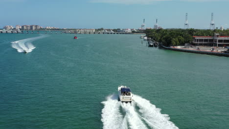 Powerful-speed-boat-cruising-Miami-waterfront-towards-port-cranes-in-the-distance