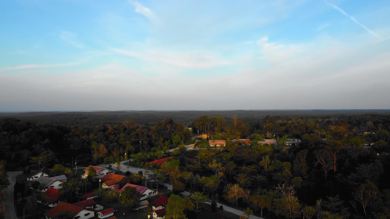 Amazing cinematic 4K sunset residential drone footage after deforestation issue consists of homes, road, trees, lake and infrastructure in the middle of tropical forest located in Riau, Indonesia