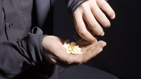 suicidal man pours capsule pills into his hand.