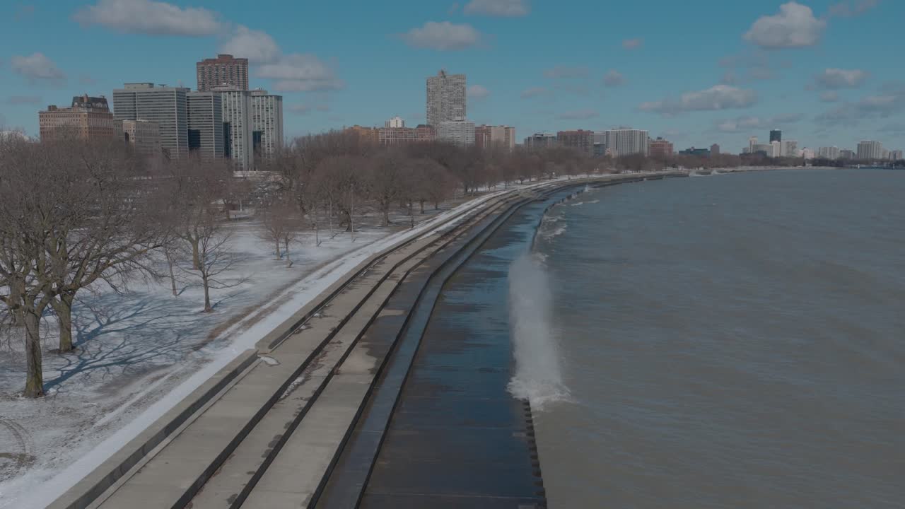Ondas quebrando ao longo da orla de Chicago em um dia de inverno nevado em uma tomada panorâmica de drone
