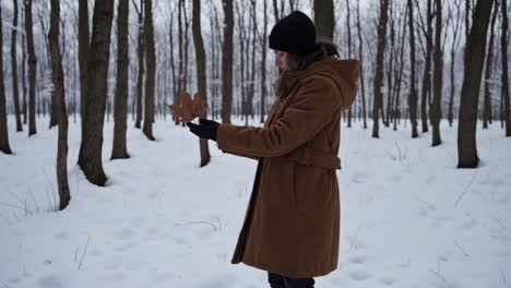 a person holding a dry leaf in a snowy winter forest