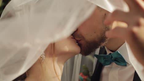 Newlyweds.-Caucasian-groom-with-bride-kissing-under-the-veil.-Wedding-couple