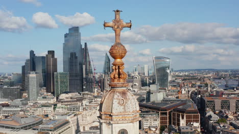 Panoramakurvenaufnahme-Eines-Dekorativen-Kreuzes-Auf-Dem-Kirchturm-Mit-Stadtbild-Im-Hintergrund.-Gruppe-Von-Hohen-Modernen-Wolkenkratzern-Im-Geschäftsviertel-Der-Stadt.-London,-Vereinigtes-Königreich