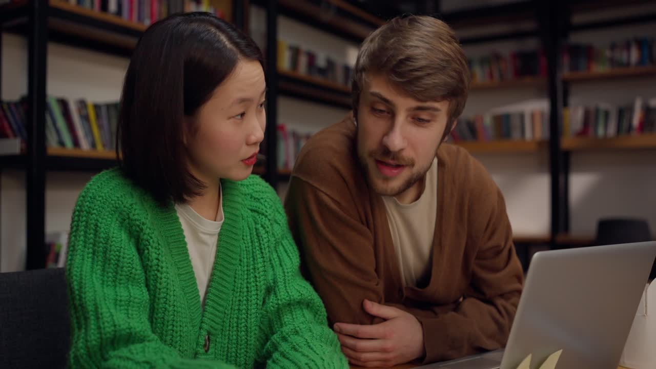 dos personas estudiando en una biblioteca