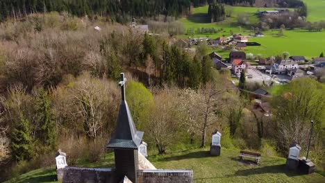 Drone-Shot-of-a-Chapel-on-top-of-a-Hill-in-front-of-Alpine-Mountains