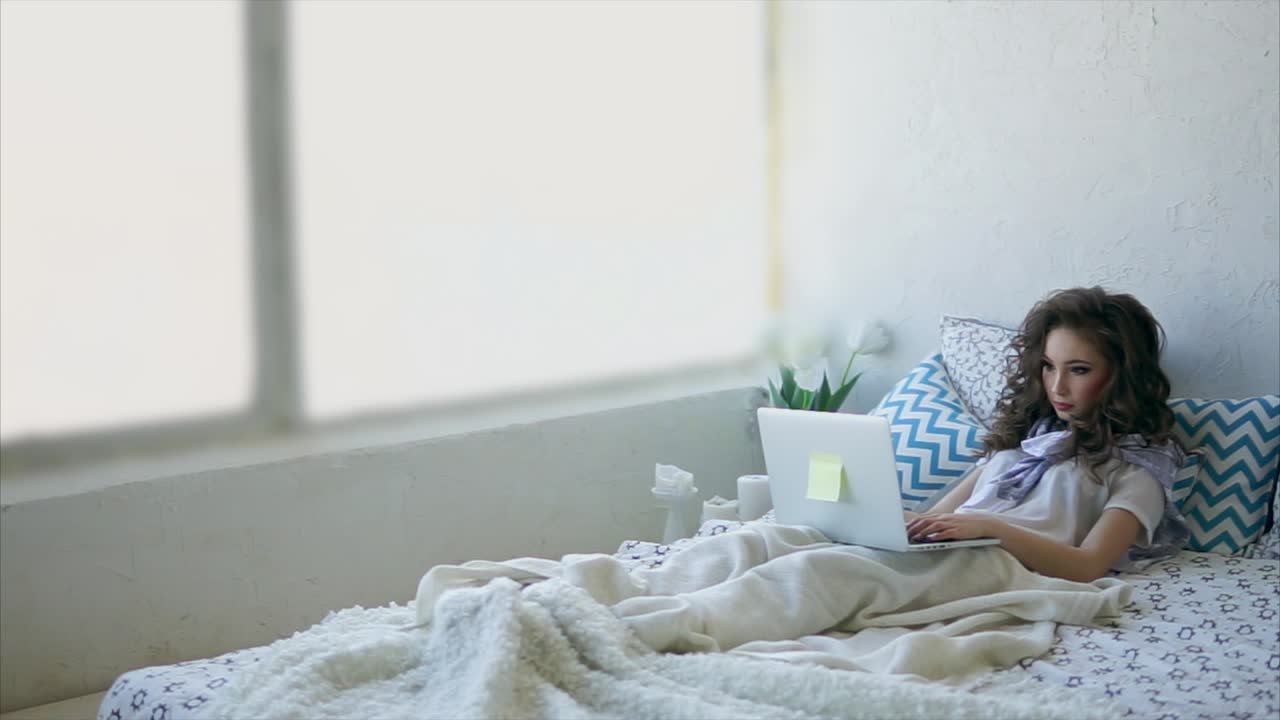 침대에 노트북으로 일하는 여자