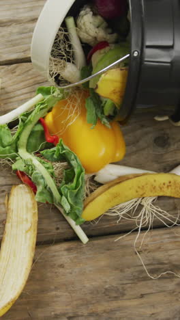 video of white compost bin with organic waste lying on grey wooden background