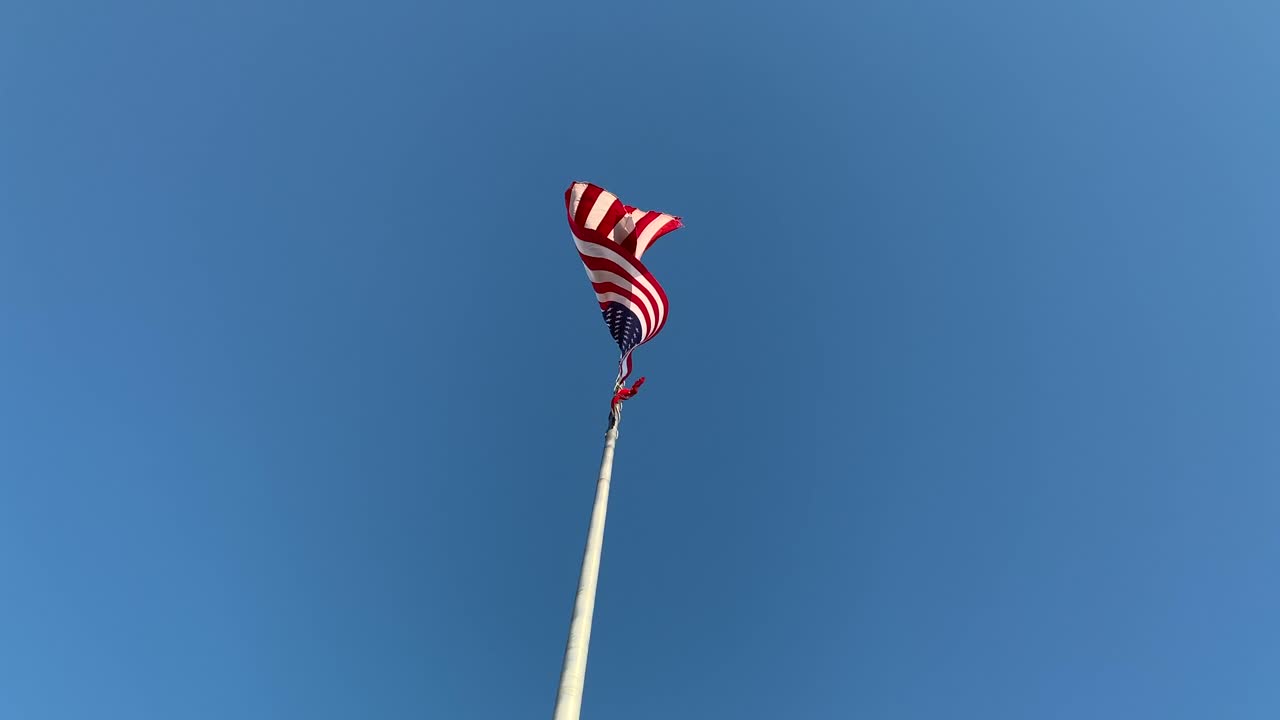 American flag on pole against blue sky, no person