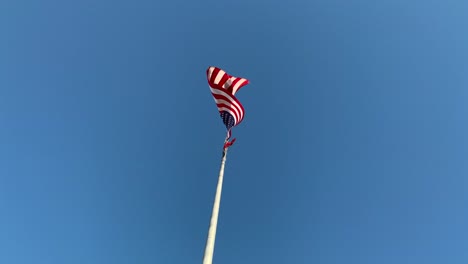 american flag on pole against blue sky, no person