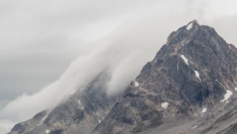 time lapse view of clouds and fog rolling over mountain peaks and down the slopes