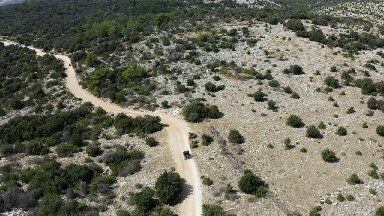 Dune Buggy Travelling Along Narrow Path in Vast Mountainous Landscape, Aerial View