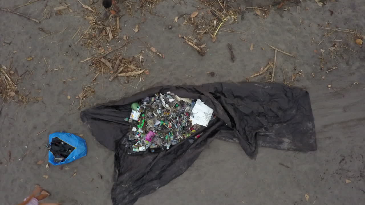 Aerial rises from tarp of trash during beach clean up event in Bali