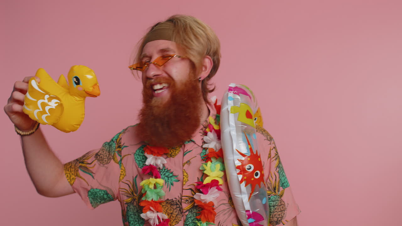 viajero turista joven hombre hippie celebrando, bailando burlándose con la natación juguete de pato inflable
