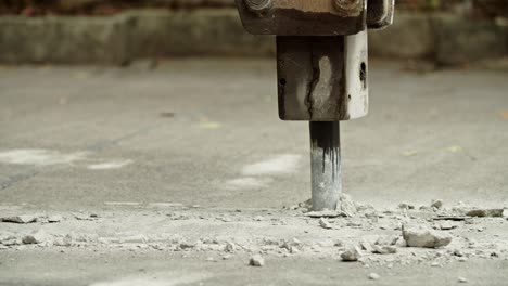 close-up of excavator hydraulic arm rock breaker working on concrete road with sound